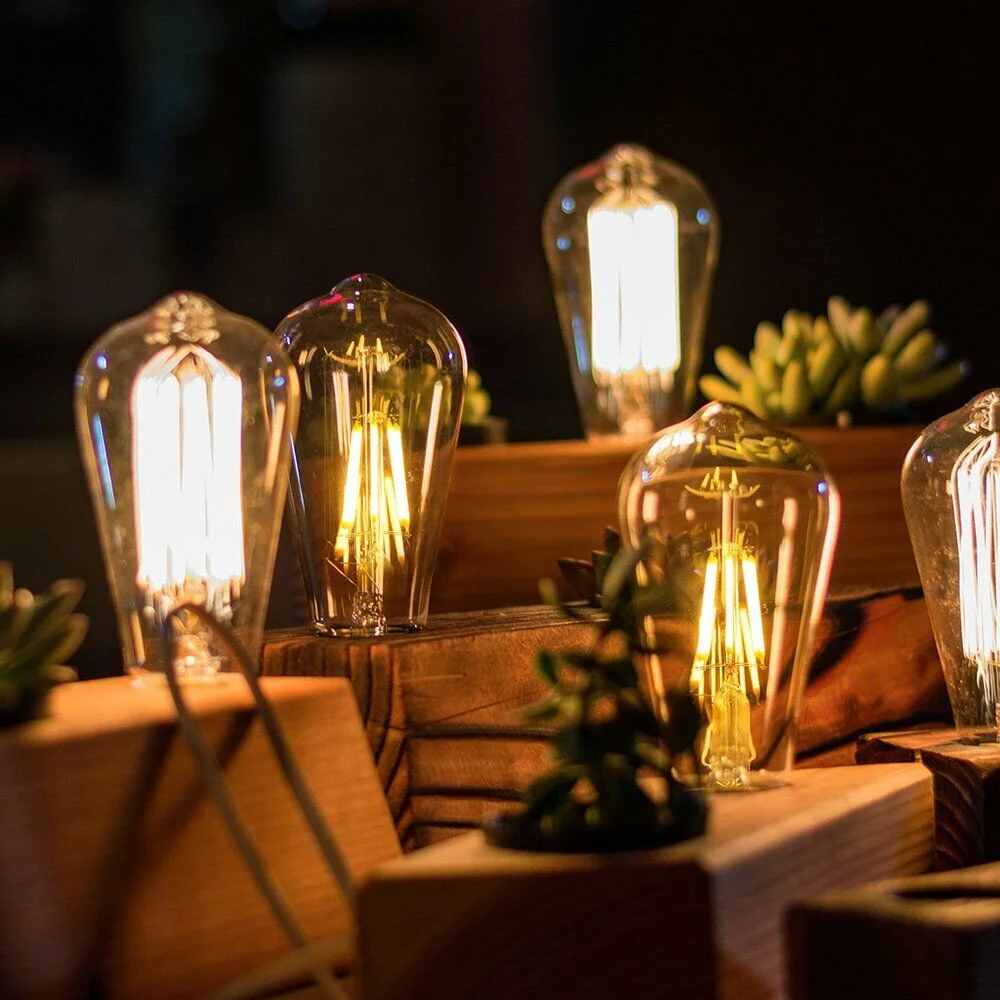 Ten vintage ST64 LED bulbs with E27 sockets and visible filaments glowing warm white light