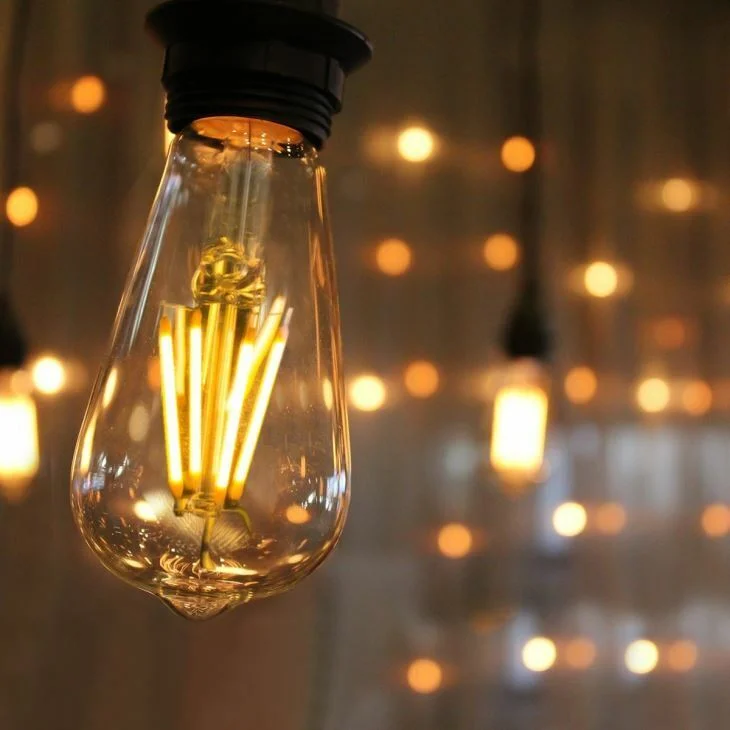 Ten vintage LED bulbs with ST64 shape and E27 base, glowing warm white filaments on a wooden surface