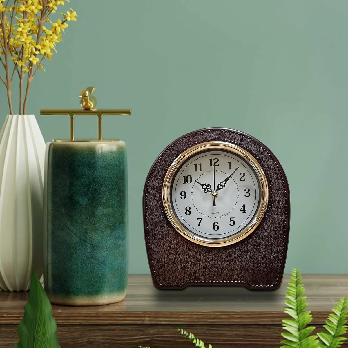 Vintage style black leather mantel clock with round face and white numerals on a wooden table background