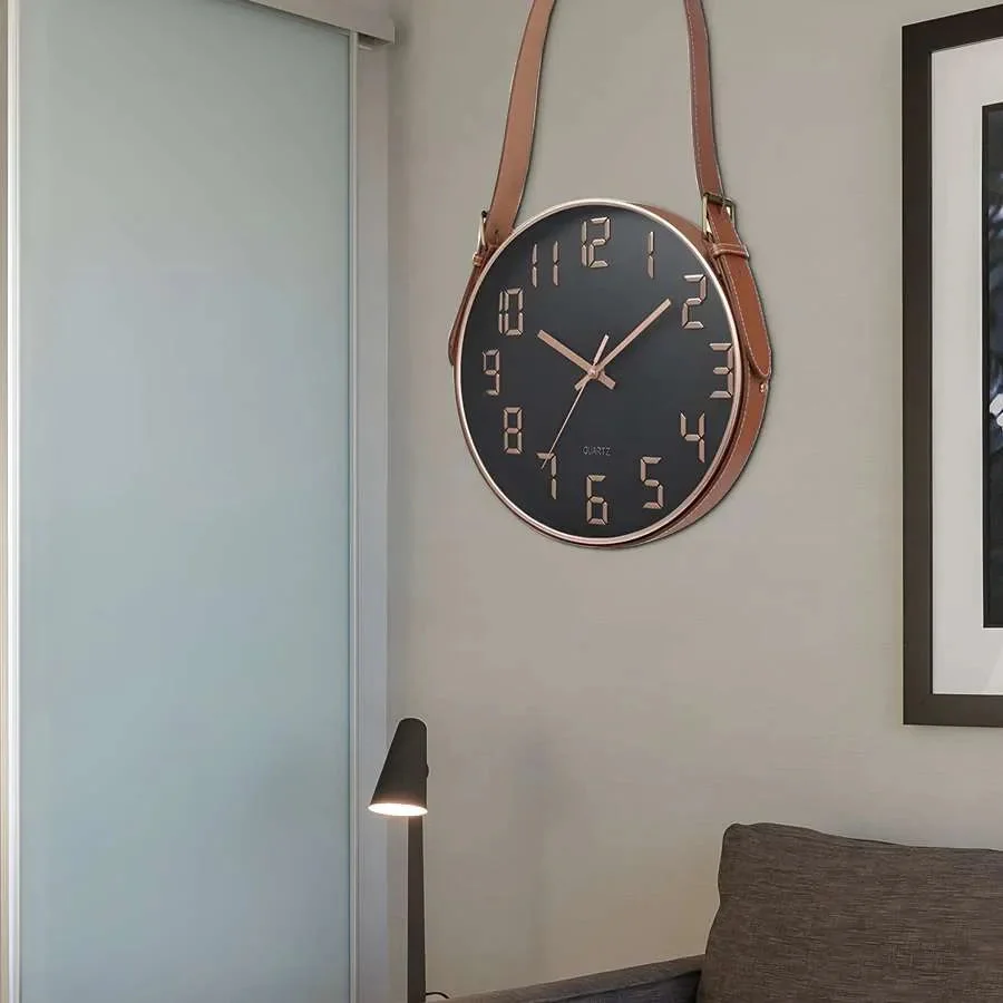 Modern round wall clock with concrete face and brown leather strap hanging on white wall background