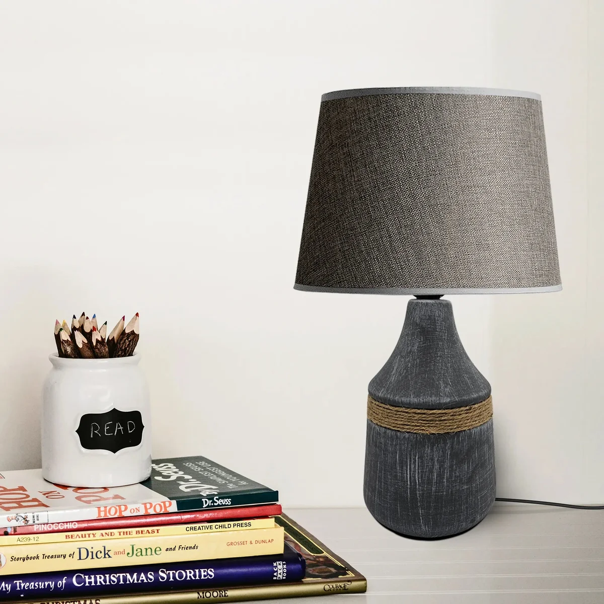 Modern minimalist table lamp with black fabric coolie shade and ceramic base on a white background