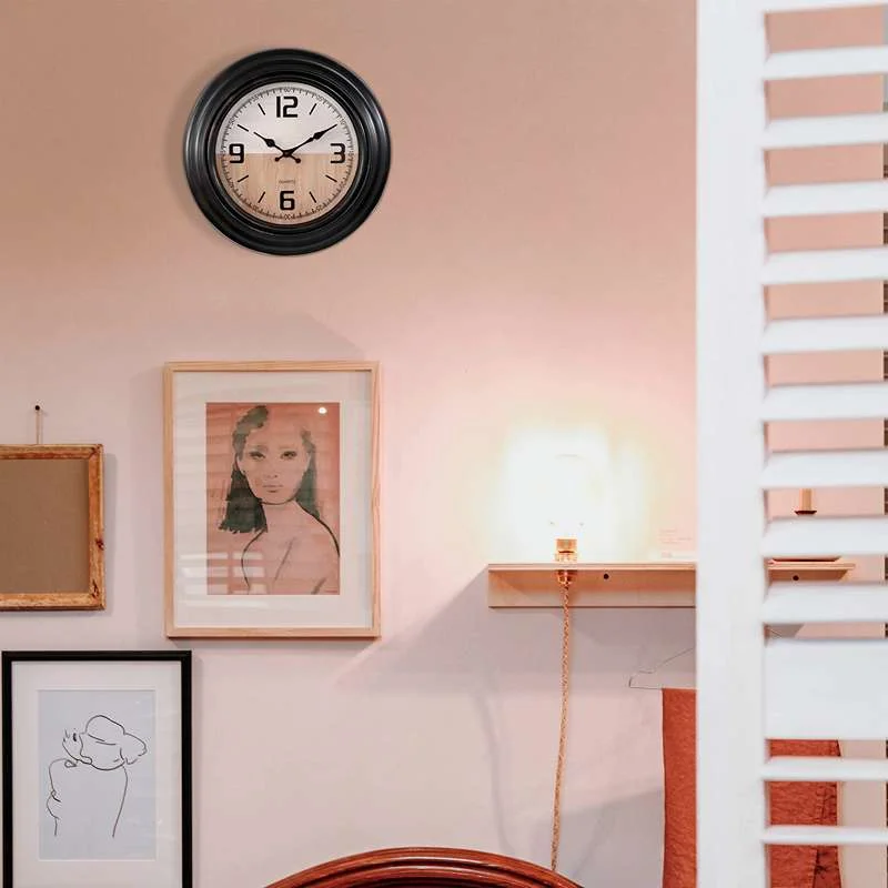 Black round vintage plastic large wall clock with clear numbers and hands, sleek shiny surface, hanging on white wall