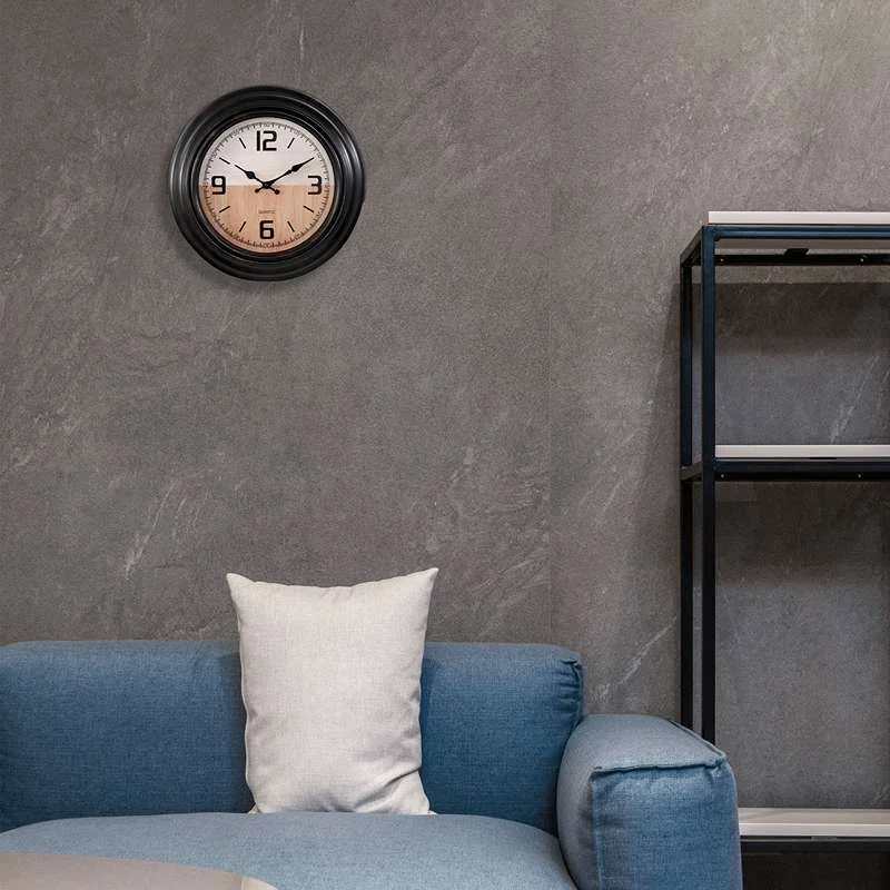 Black round vintage living room wall clock with large numbers and sleek plastic frame hanging on white wall