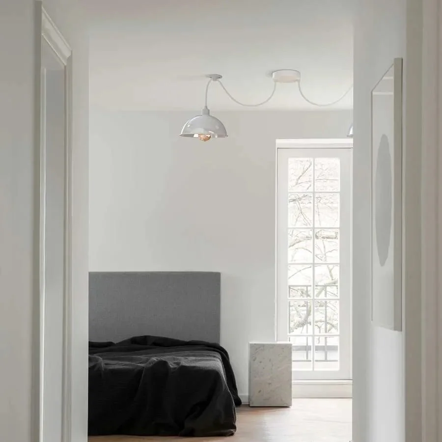 Two-shade white metal pendant light with adjustable cables and industrial spider design hanging against a plain background