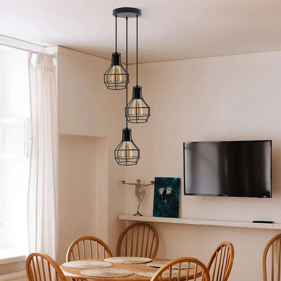 Three black metal cage shades of industrial pendant light hanging from adjustable cables against a white background