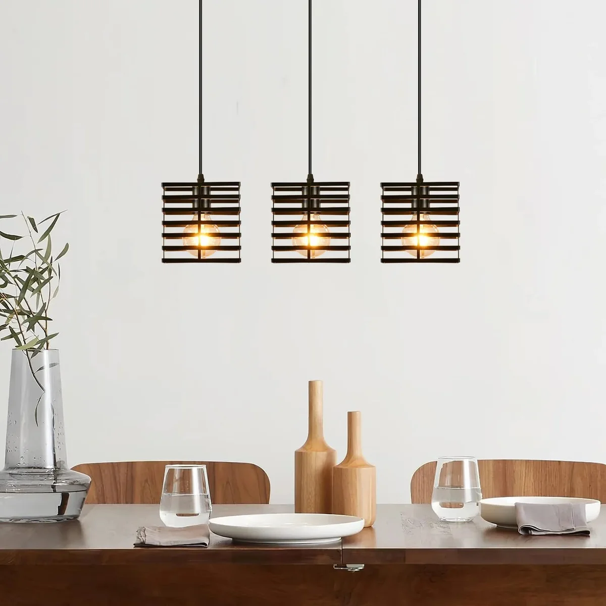 Three black metal pendant lights with square wire cages hanging at different heights against a white background