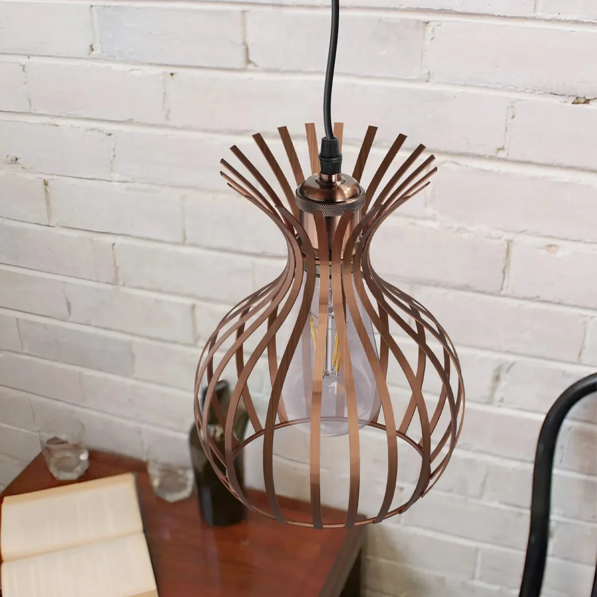Copper metal wire cage pendant light hanging from ceiling with adjustable cable and vintage industrial design