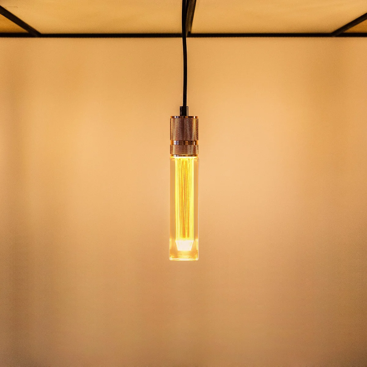 Vintage tubular E27 LED bulb with amber glass and spiral filament, emitting warm 2000K light for decorative use