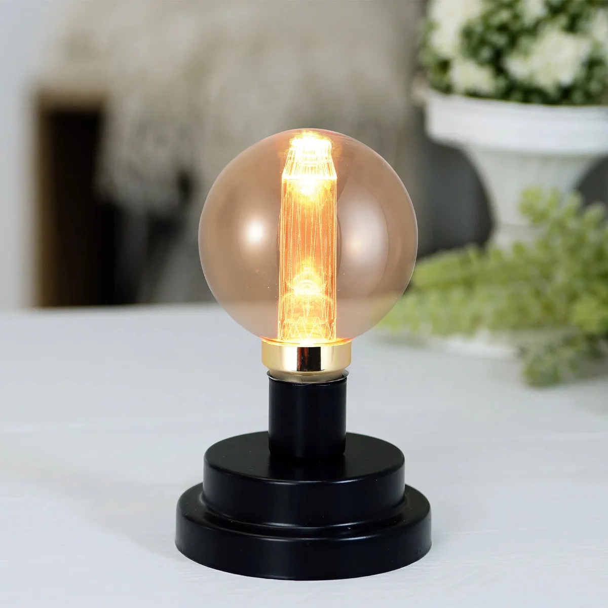Vintage G80 quad-loop filament bulb glowing warm golden light in antique amber glass with E27 screw base