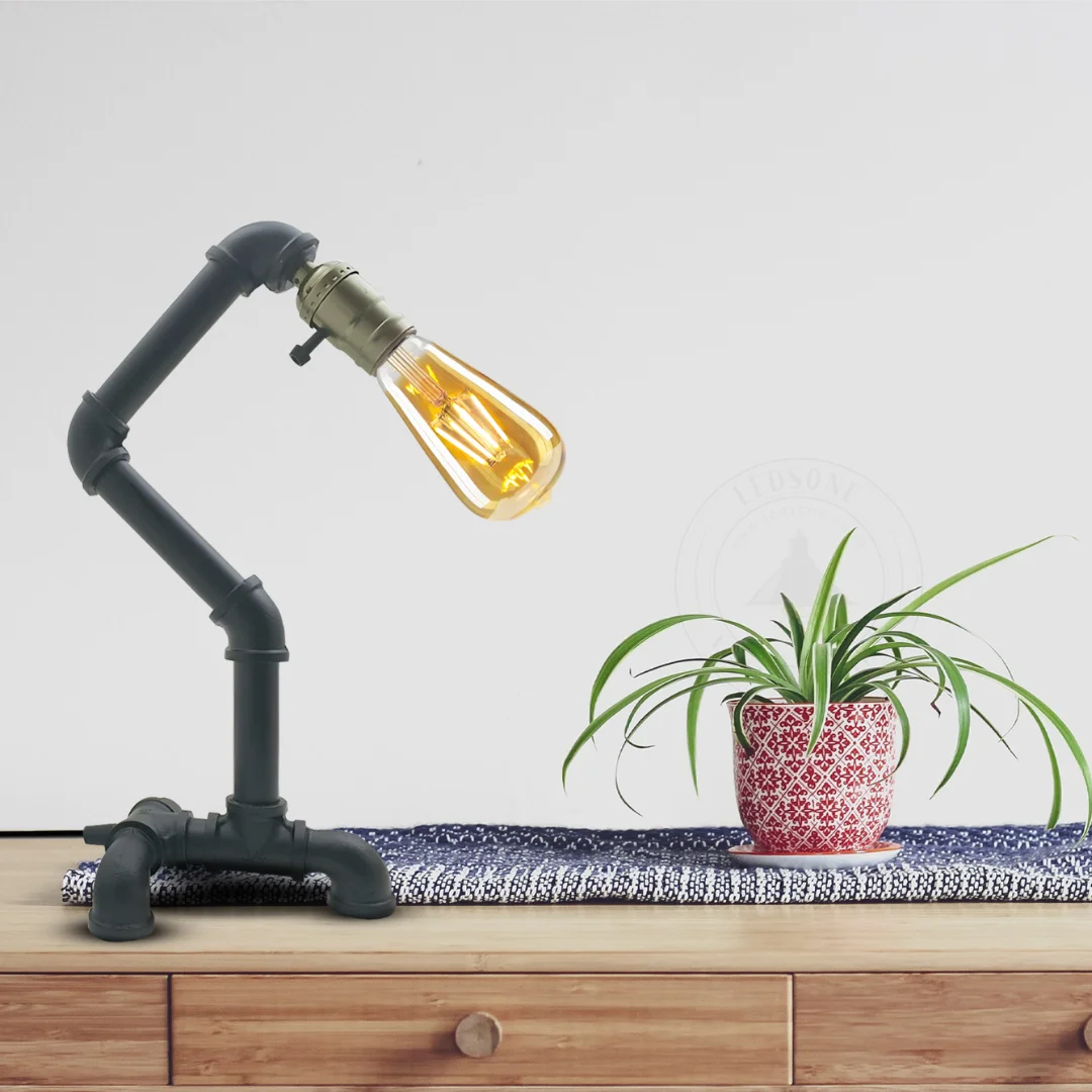 Black vintage pipe desk lamp with industrial steel pipe design and rust finish on wooden surface against white background