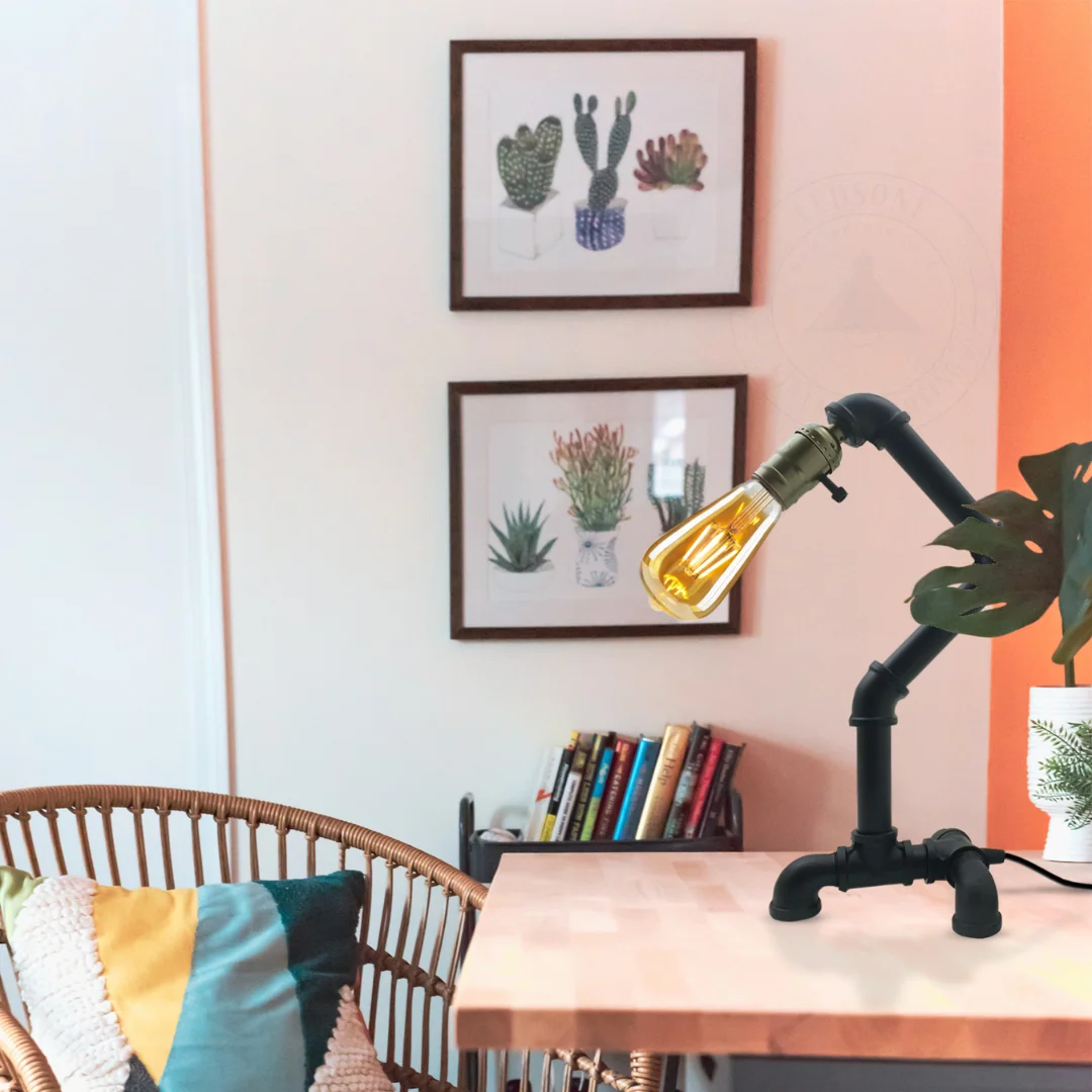 Black vintage industrial table lamp made of metal with rust finish, pipe design, and E27 bulb base on wooden surface