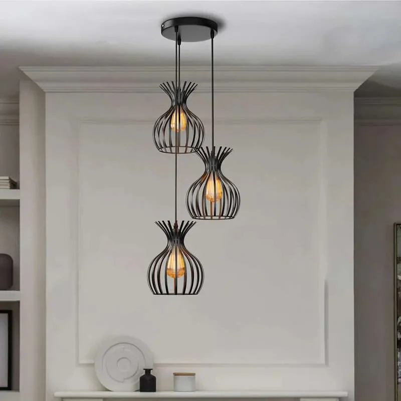 Three black metal pendant lights with wire cage shades hanging above a dining table, adjustable height cables visible