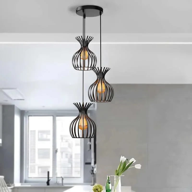 Three black metal wire cage pendant lights hanging at different heights, showcasing adjustable ceiling light design above dining table