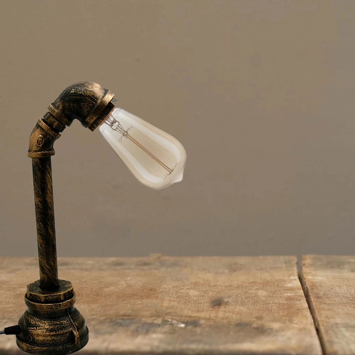 Vintage style steampunk plug in desk lamp with rustic water pipe design and brushed copper finish on wooden surface