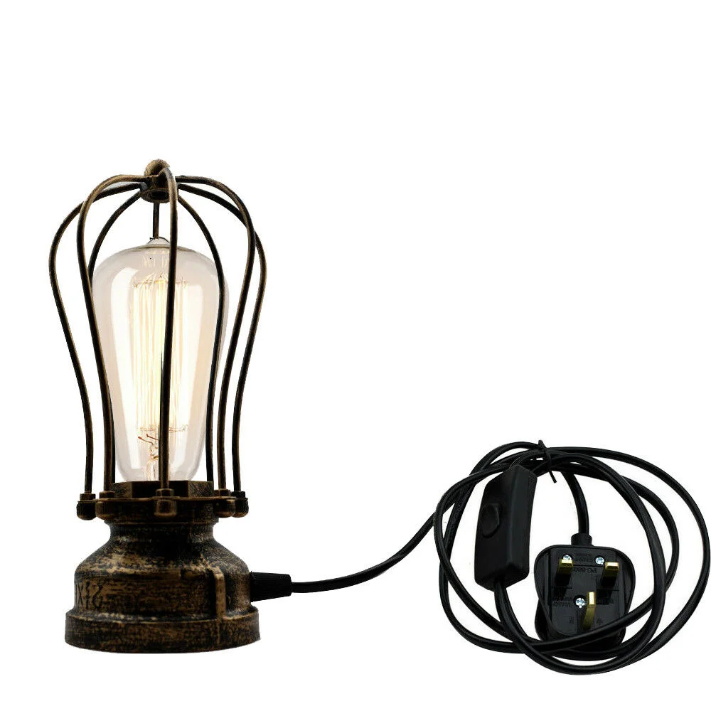 Compact industrial table lamp with black metal cage shade and visible E27 bulb on wooden desk surface