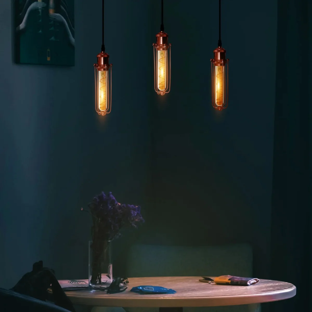 Rose gold pendant light with three rectangular wire cage shades hanging from adjustable black cords against white background