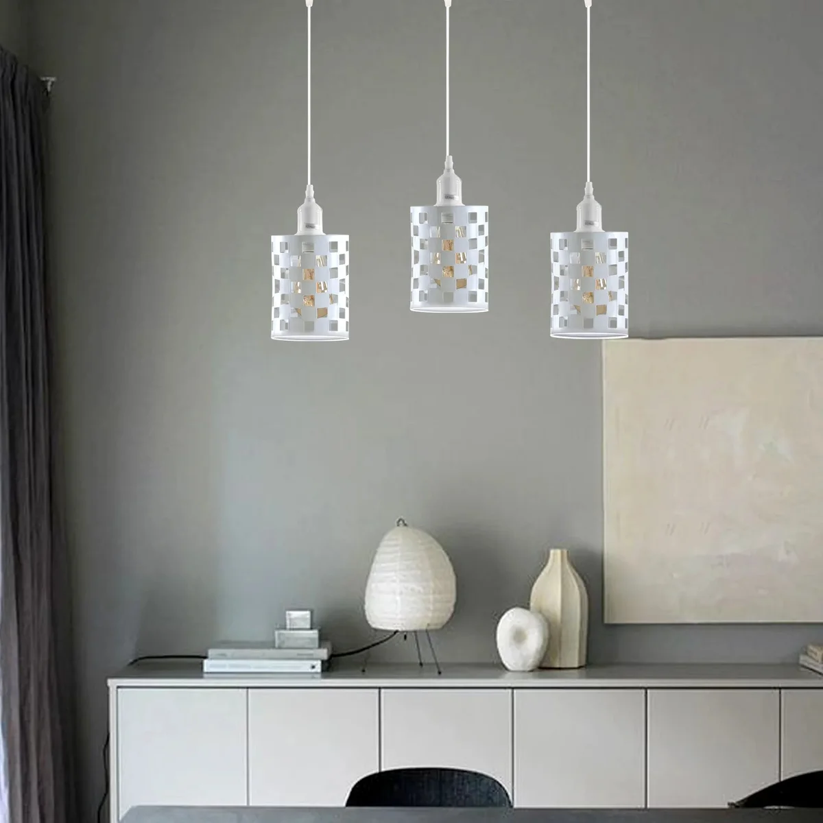 Vintage industrial pendant light with three white metal cage shades and adjustable hanging cords on a white background