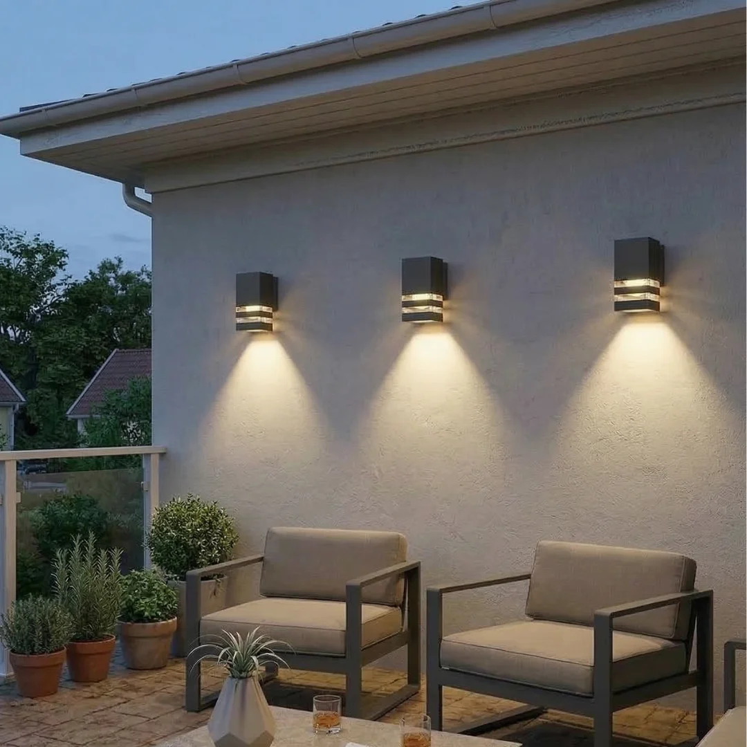 Black outdoor wall lantern with modern square design mounted on a porch wall, emitting warm white LED light