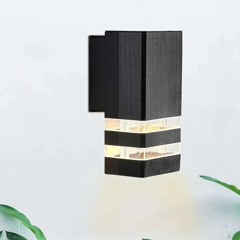 Modern black outdoor wall light with square design mounted on a wall, emitting warm white LED illumination