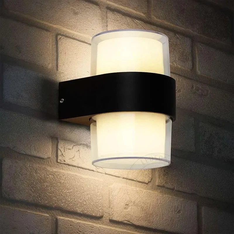 Modern black aluminum warm white LED wall light mounted outdoors, casting up and down illumination on garden wall