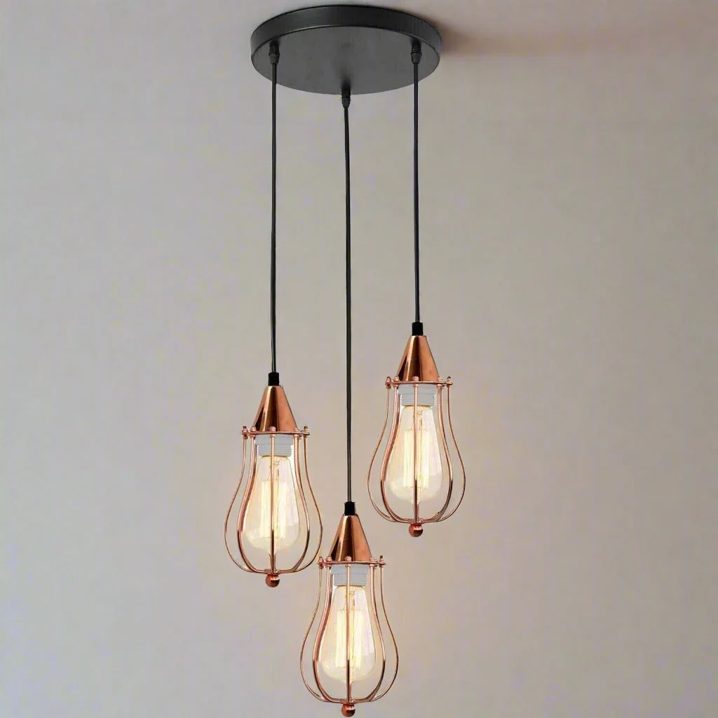 Rose gold vintage industrial metal pendant light kit with three metal cages and adjustable cables.
