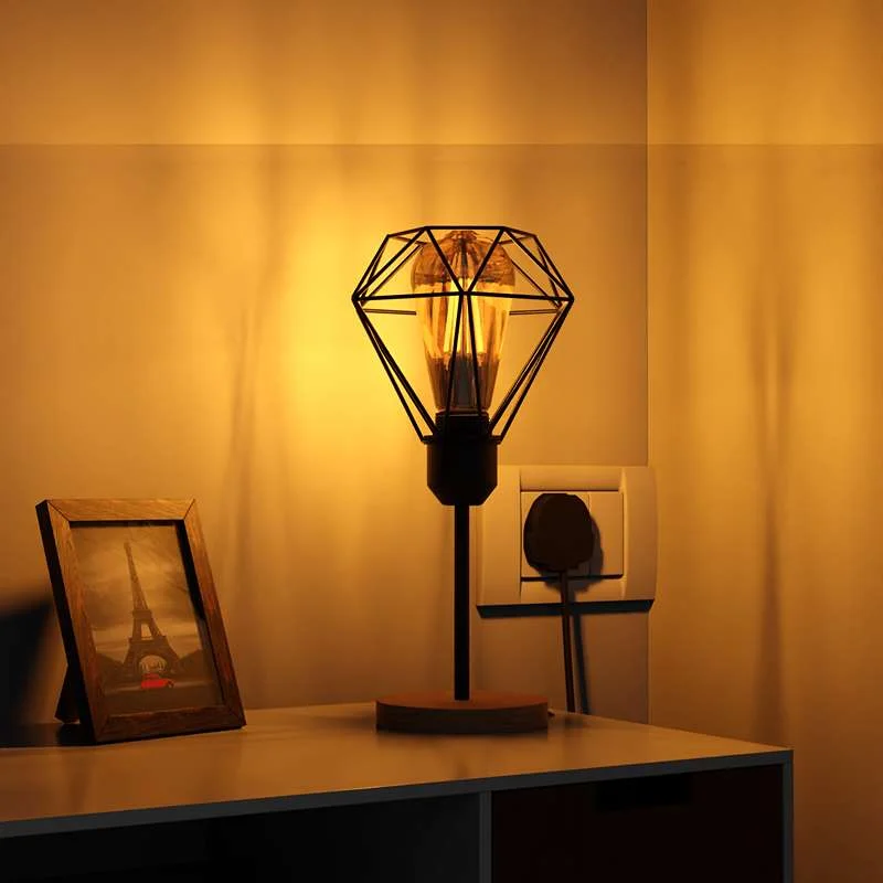 Vintage industrial desk light with diamond-shaped black metal cage, natural wood base, E27 socket, cable visible