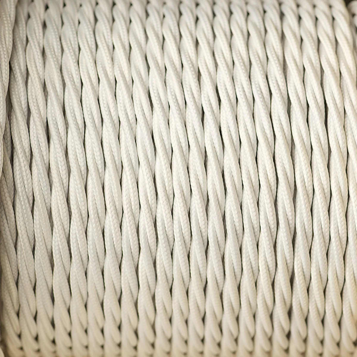 A cable of vintage twisted lighting cable in ivory fabric, coiled and ready for pendant light installation.