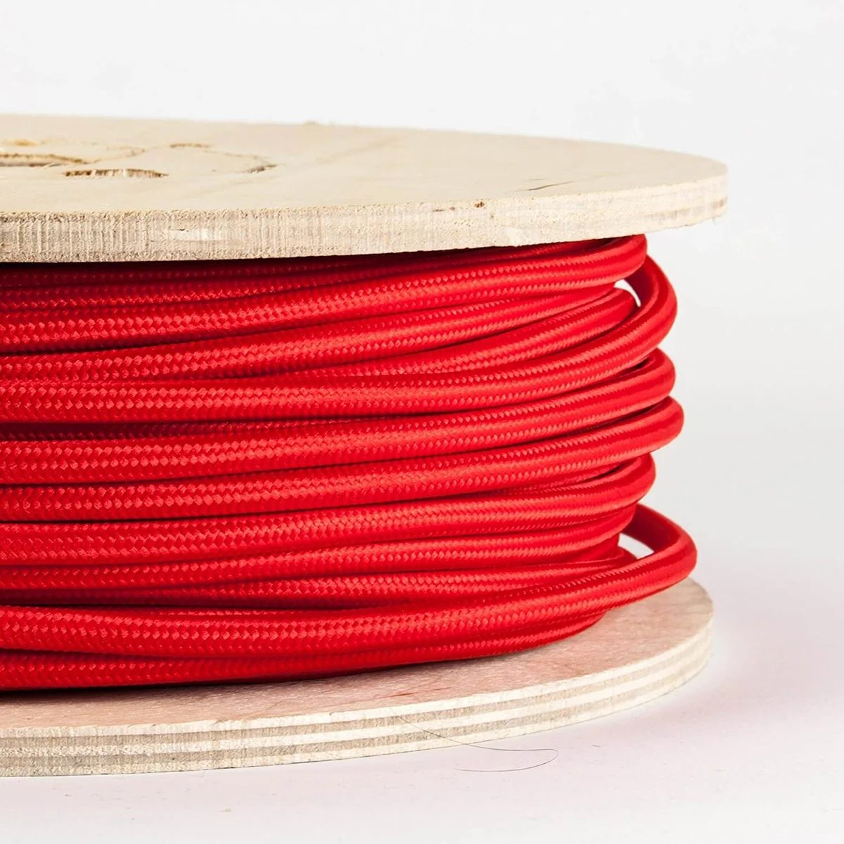 Red cloth covered lighting cable with twisted copper cores and PVC insulation, shown in a length of wire on a surface.