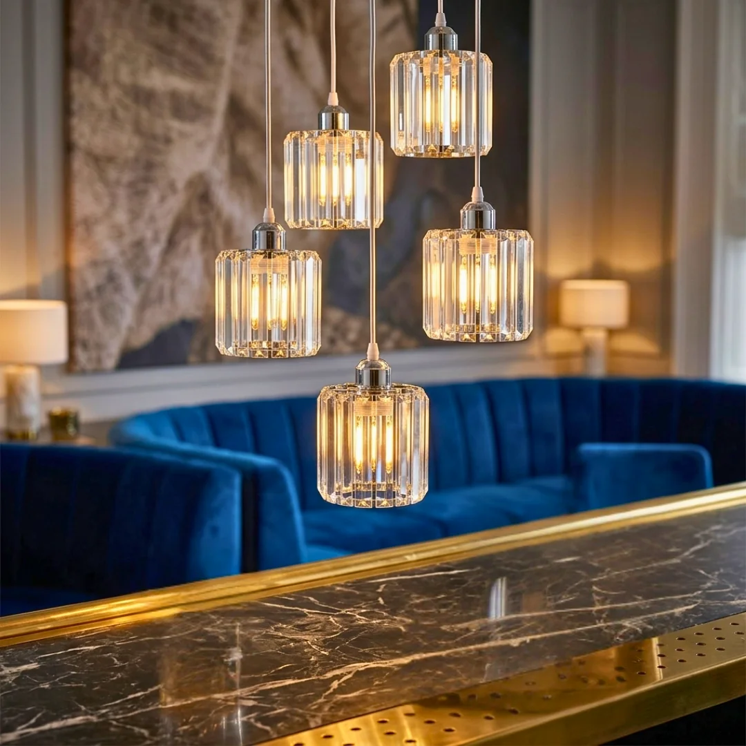Crystal pendant light with round crystal glass shade and metal frame, hanging above kitchen island
