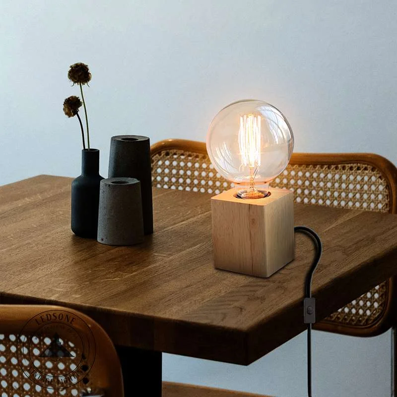 Modern table lamp with round wooden base, metal E27 holder, 2‑m PVC cord with switch.