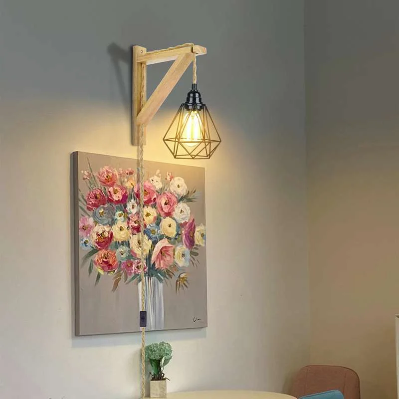 Vintage hanging lamp with black diamond cage shade, wood and hemp rope cord, metal base hanging on wall.