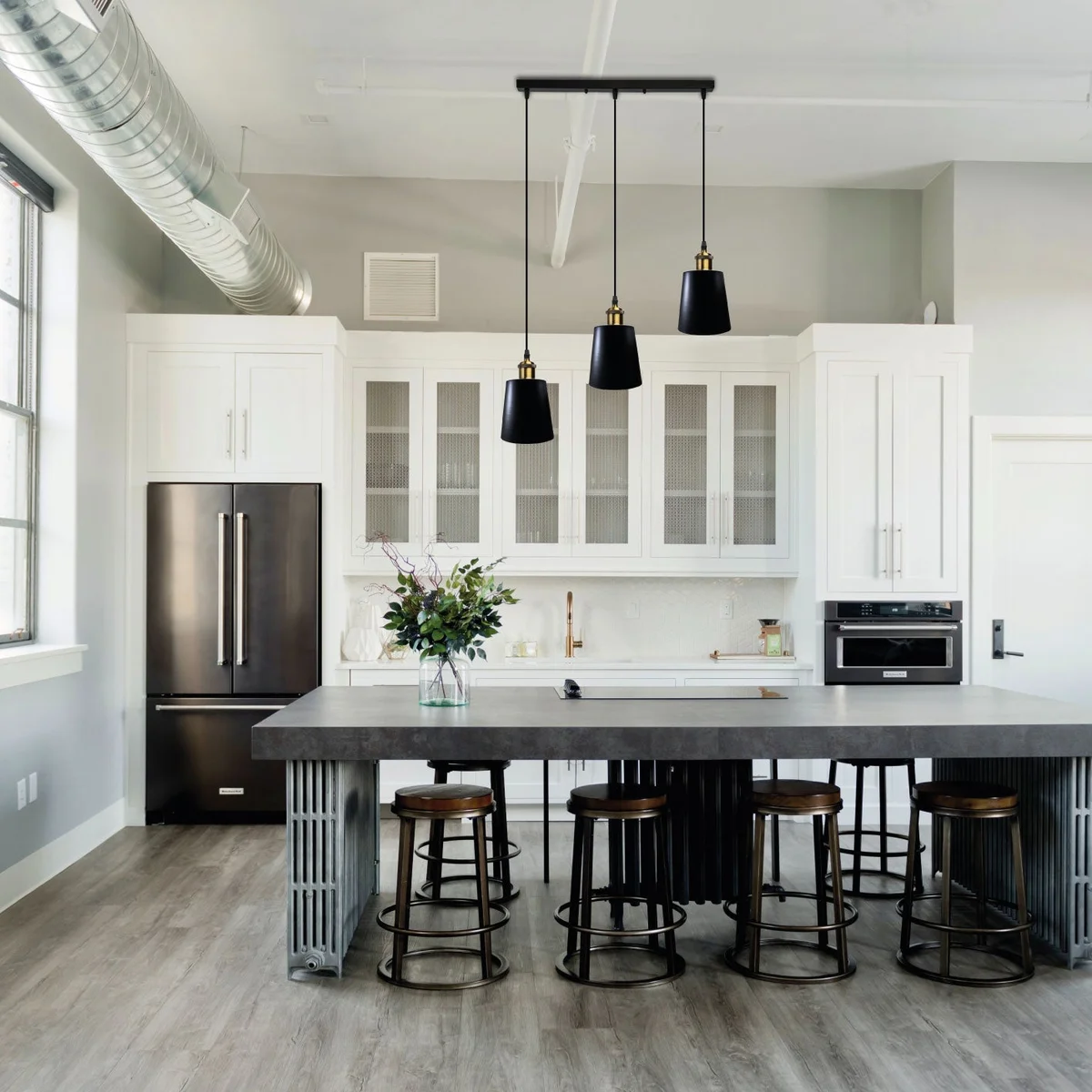 Black metal vintage industrial ceiling light hanging from ceiling with three shades and adjustable cable.