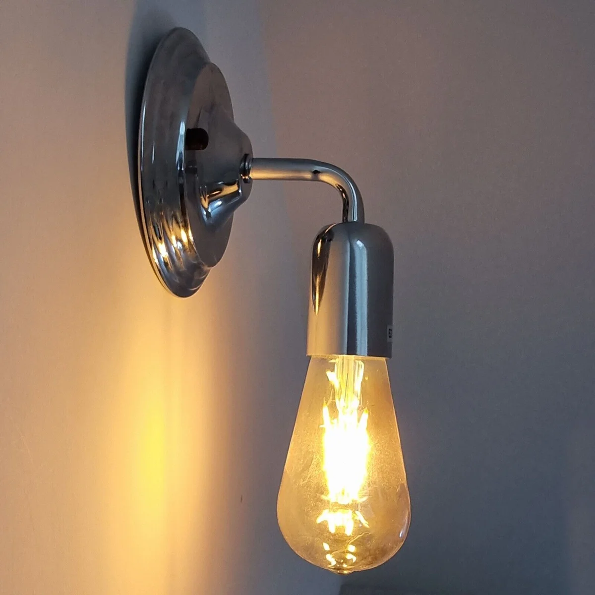 Vibrant chrome wall lamp with vintage design, polished sconce attached to wall, suitable for dimming, E27 bulb holder visible