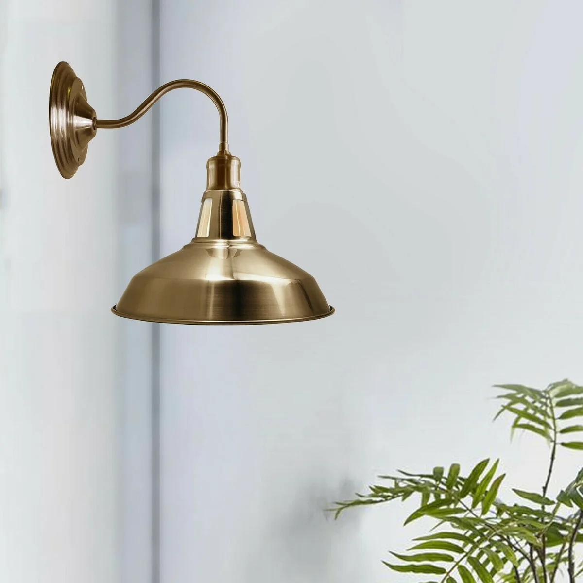 Barn slotted wall lamp with high polished yellow brass metal shade hanging on a plain wall