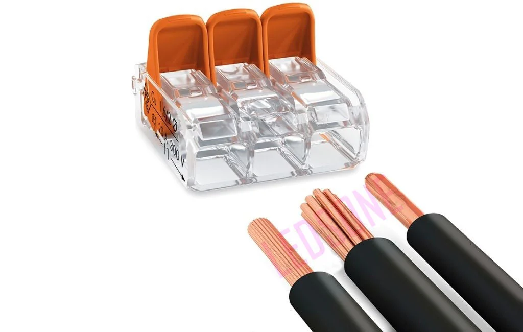 Clear and orange 3‑way spring lever push‑fit reusable wire connector with compact levers and test hole.