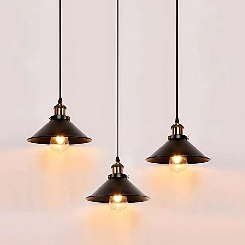 Three industrial pendant lights with black metal shades hanging over a dining table