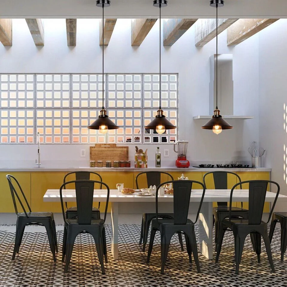 Three black industrial pendant lights with metal lampshades and adjustable cables hanging above a dining table.