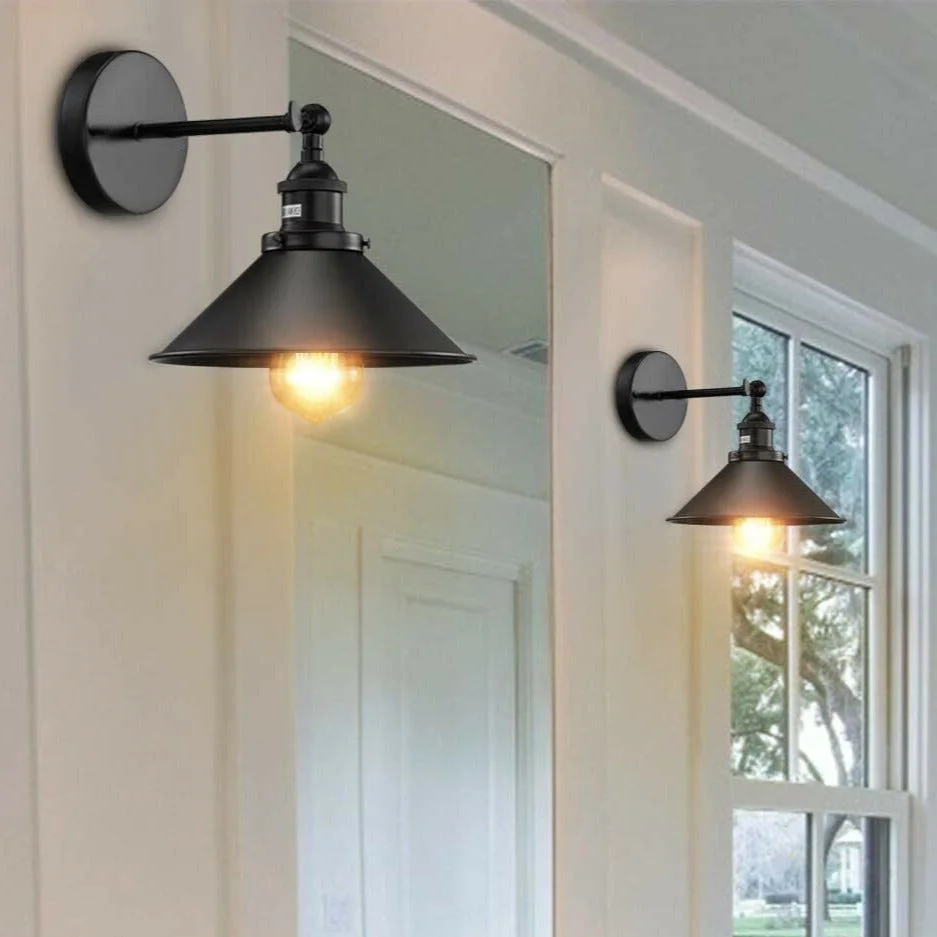 Black metal wall sconce with cone lampshade mounted on wall.
