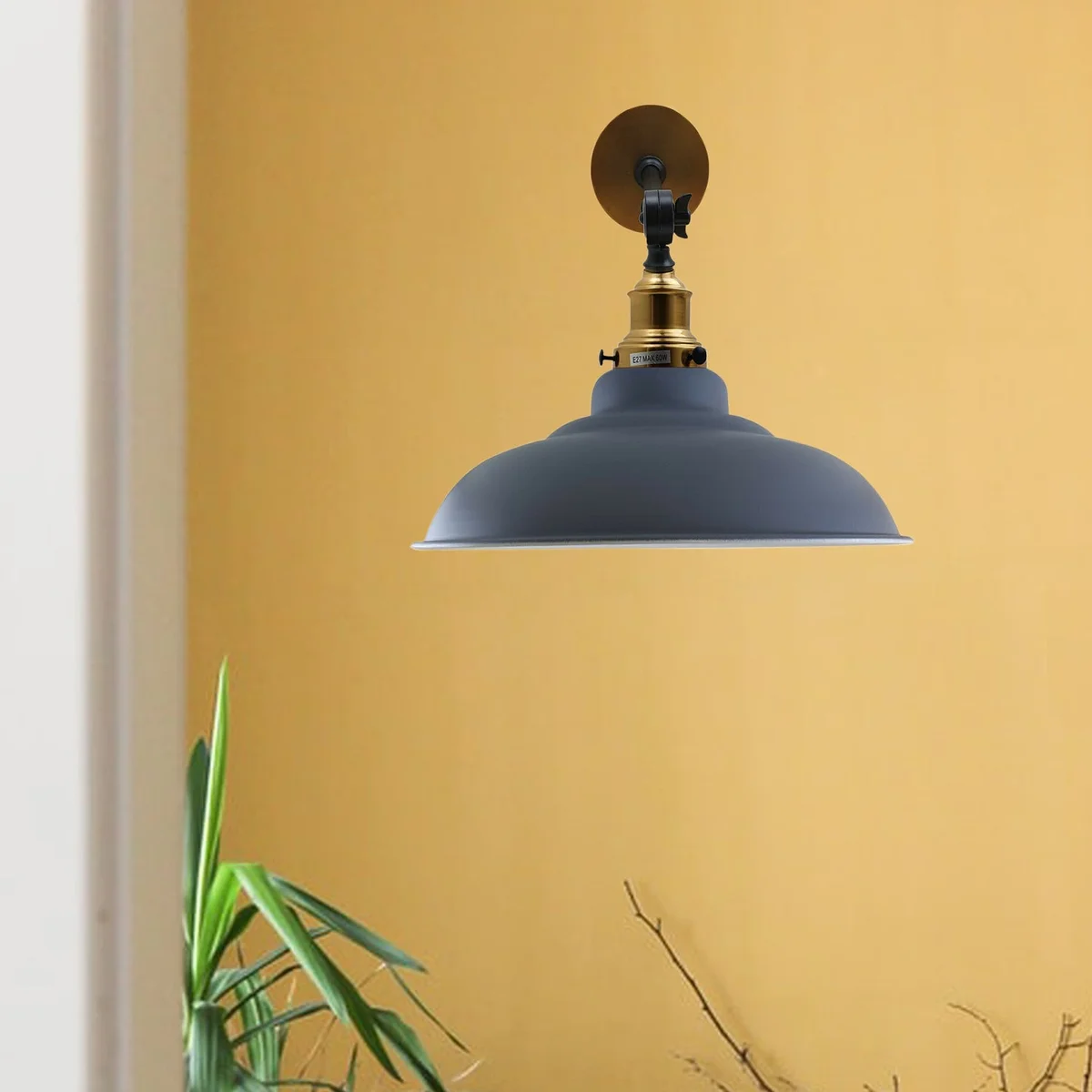 Adjustable vintage wall light with curved metal shade, adjustable arm and Edison bulb, mounted on a wall.