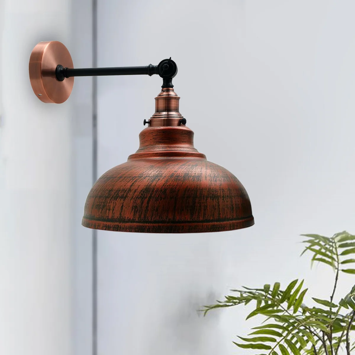 Rustic wall lamp with a curved red metal dome shade, mounted on a wall, showcasing vintage industrial design.