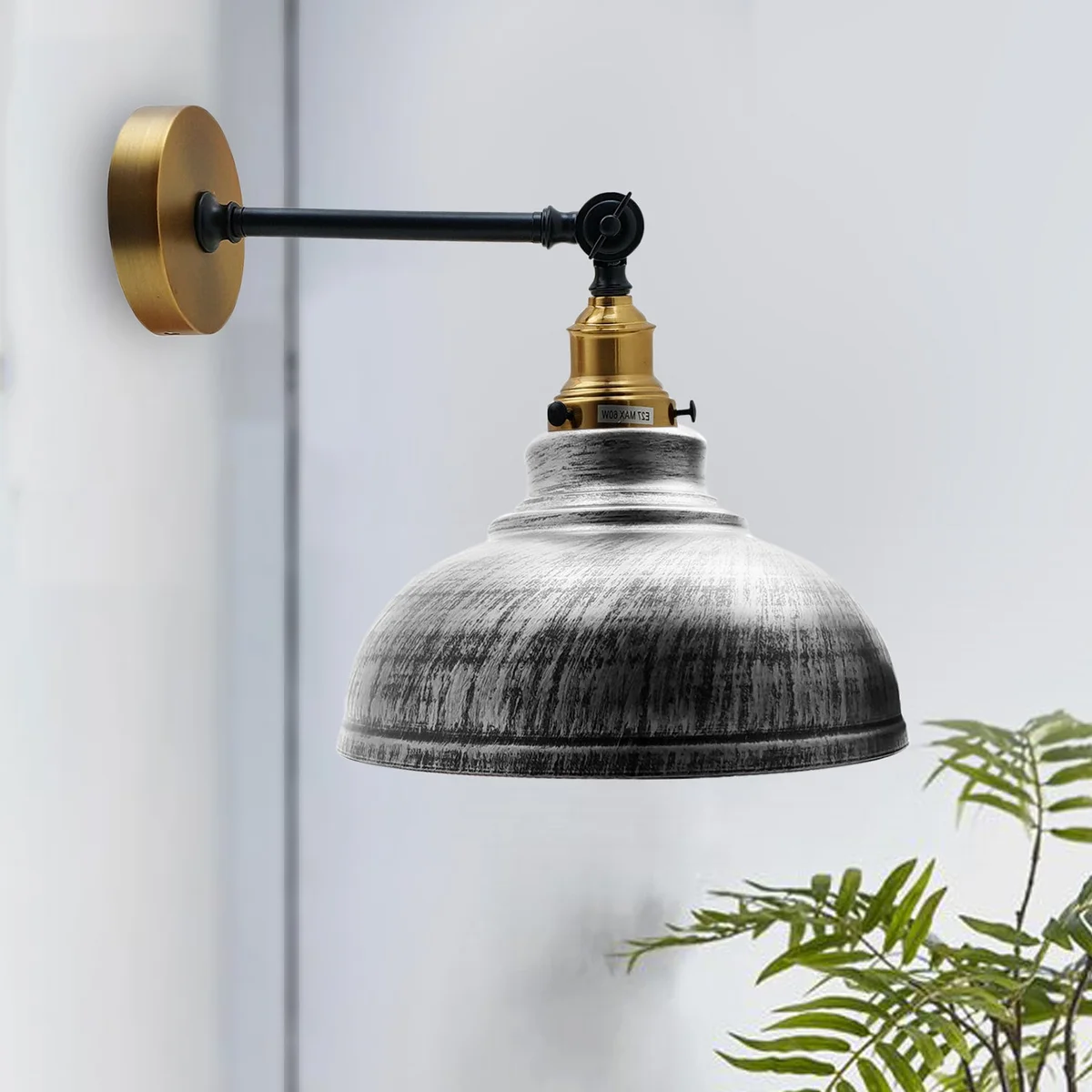 Adjustable wall lamp with curved brushed silver metal shade and metal arm on a wall.