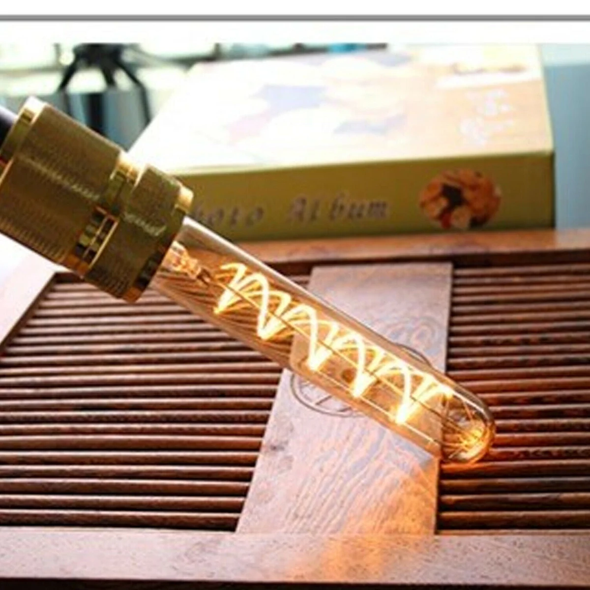 vintage LED filament bulb with amber glass, thin metal cage, glowing amber light, suitable for lamp fixtures
