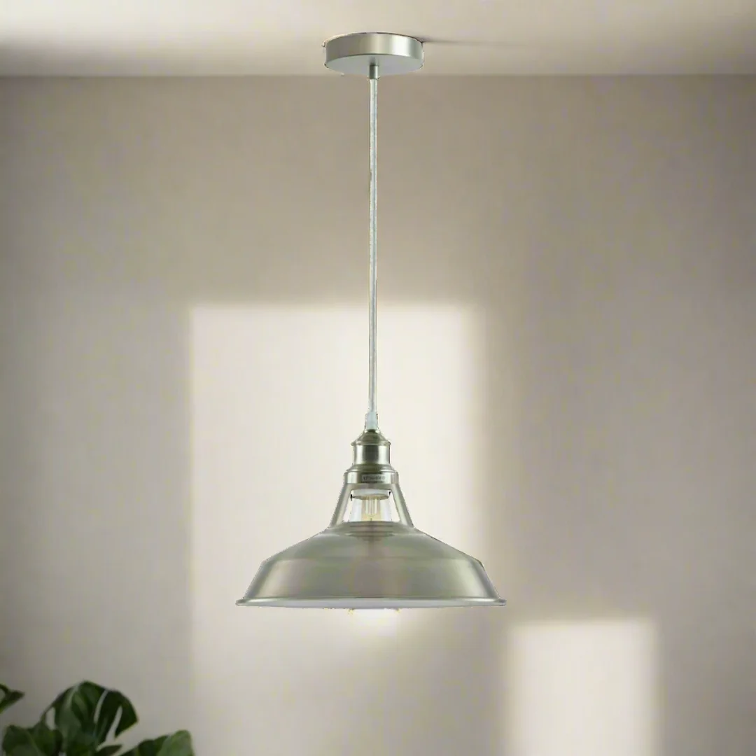 Satin nickel industrial pendant light with vintage lampshade, matte metal frame, hanging over kitchen island.