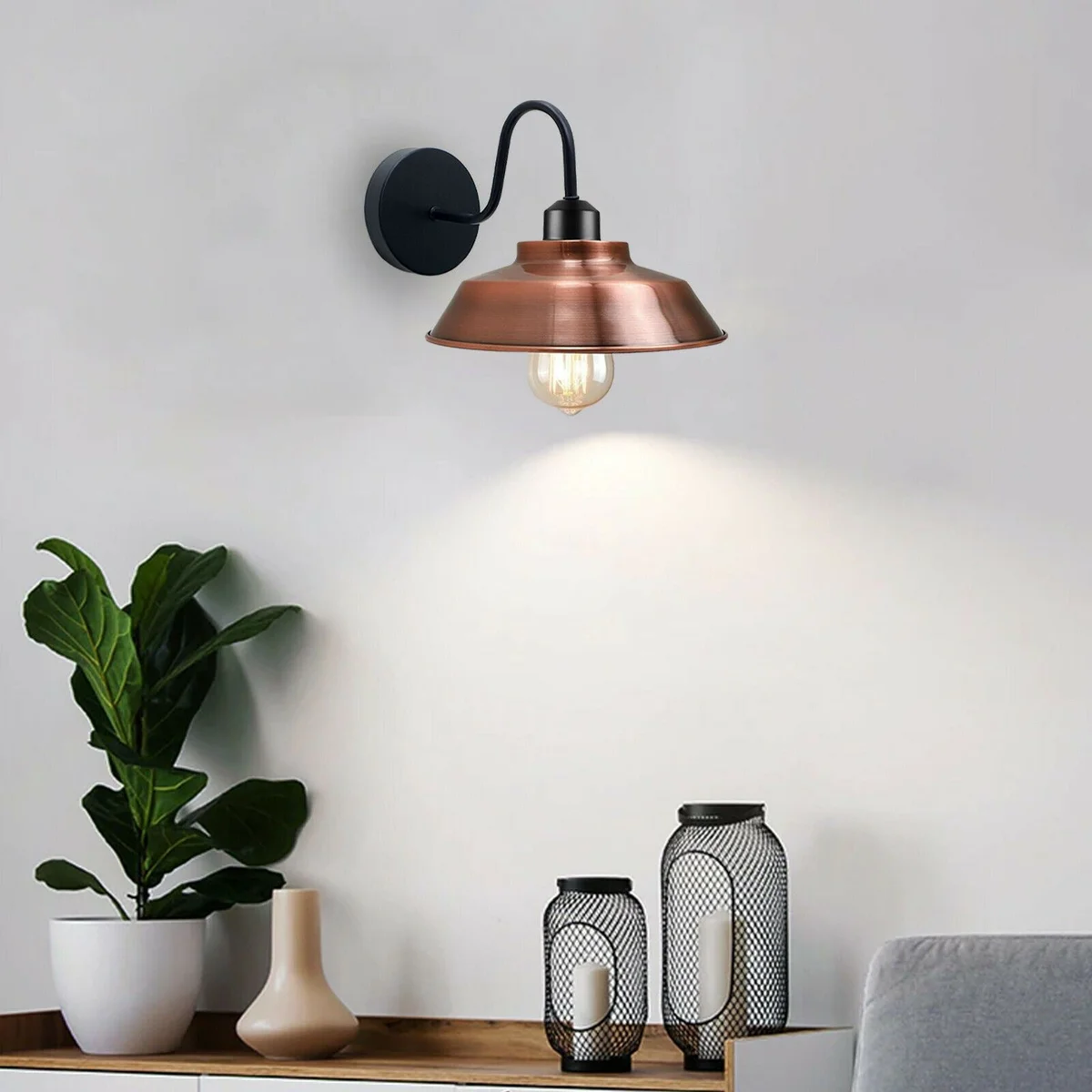 Indoor metal wall lamp in rustic industrial style, curved gooseneck arm, dome shade, brushed metal finish, mounted on wall.