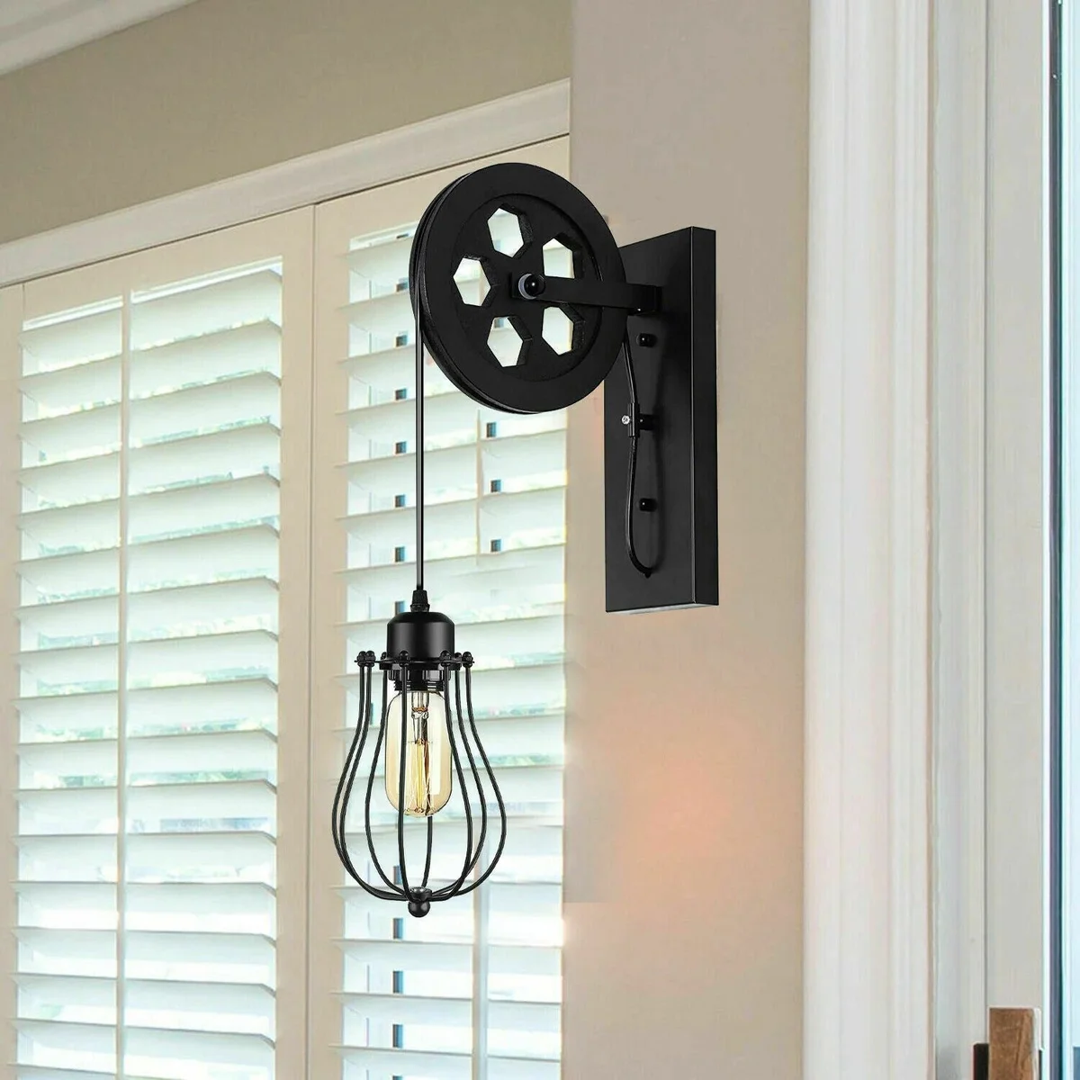 Vintage wall sconce with metal pulley wheel, wooden base, black finish, balloon-shaped shade and adjustable hanging wire.