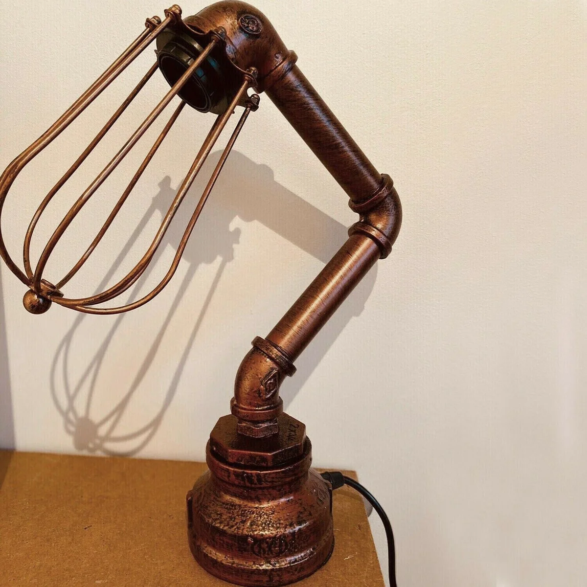 Steampunk metal desk lamp with water pipe body, protective wire cage shade, E27 socket, black finish.