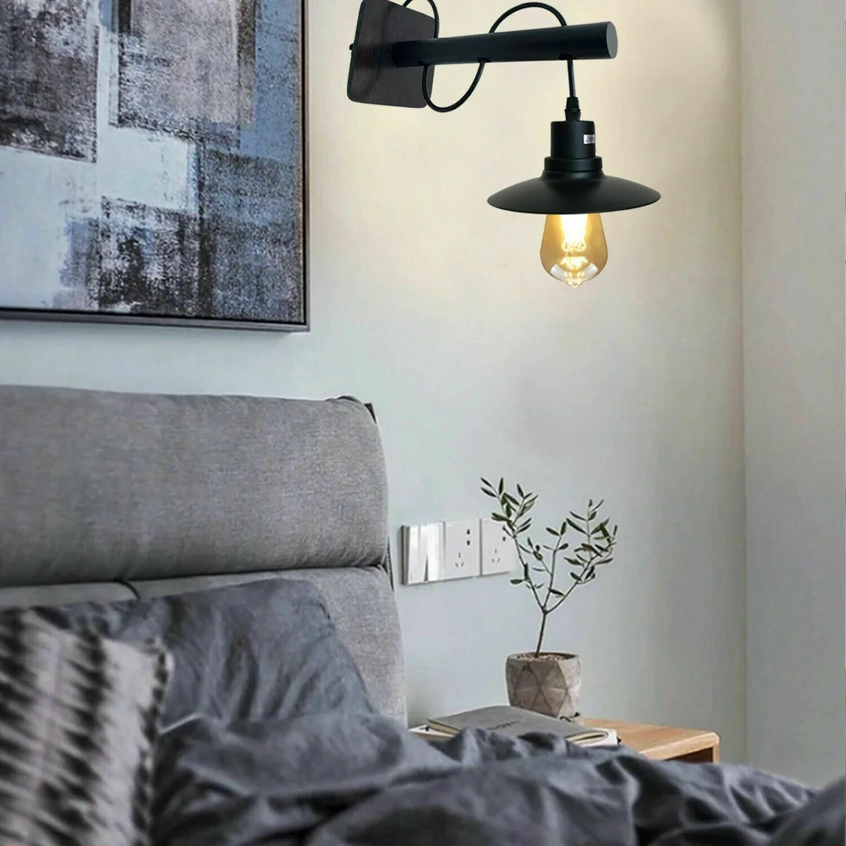 Black wall sconce with modern industrial metal design, suspended from wall and casting downward light