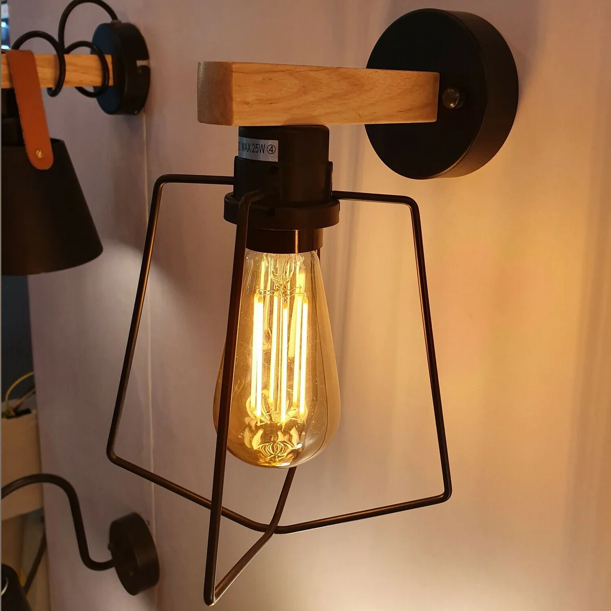 Black metal industrial wall sconce hanging on wall, featuring a unique shape and dimmable power.