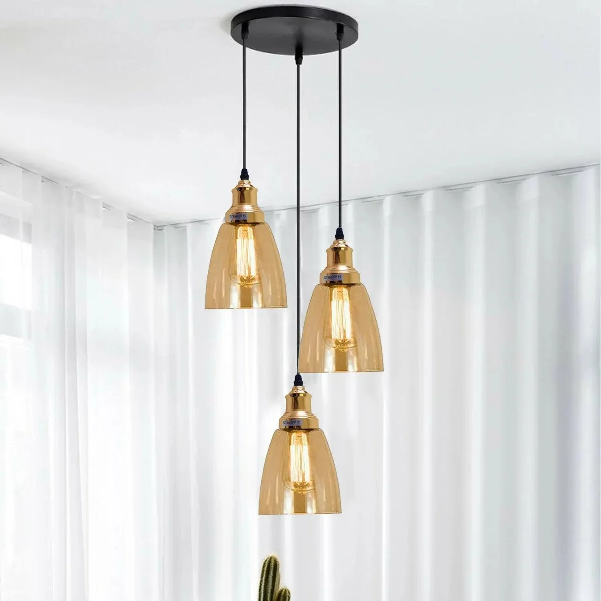Industrial pendant light with three high‑clarity amber glass cone shades hanging from adjustable cables over a metal base.