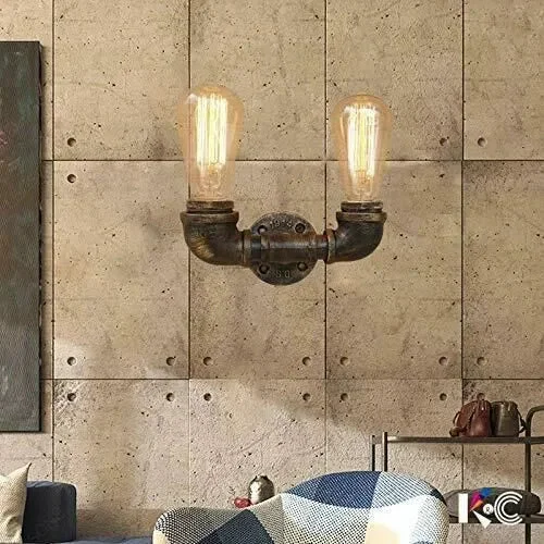Industrial pipe wall light made of metal with a brushed copper finish, featuring two bulb sockets, mounted on a wall.